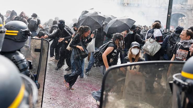 Protesters navigate tear gas and debris during a mass demonstration in Paris, reflecting widespread intergenerational discontent., AI generated