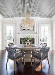 Glass bubble chandelier over a white oak dining table in a transitional dining room featuring leather and wood dining chairs and a set of a white wing back dining chairs at the end of the table under a mustard yellow ceiling. Ivory Cascading Chandelier Over Round Light Oak Dining Table Transitional Dining Room