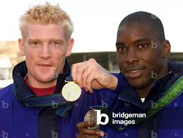 Image of Britain's Iwan Thomas (L) holds his gold medal alongside compatriot
