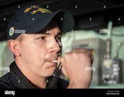 Boatswain's Mate 3rd Class Garrett Hinten sounds the boatswain's pipe to  call the crew of the San Antonio-class amphibious transport dock ship USS  Green Bay (LPD 20) to dinner. Green Bay is