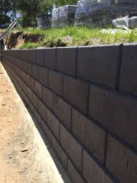 Concrete retaining wall blocks are easy to install and ideal for building soil retaining walls, reclaiming sloped land, reducing erosion and even creating feature garden walls, planter boxes and veggie patches. Austral Heron Charcoal Smooth Face Retaining Wall By Ilandscape Com Au Landscaping Retaining Walls Cinder Block Walls Black Brick Wall