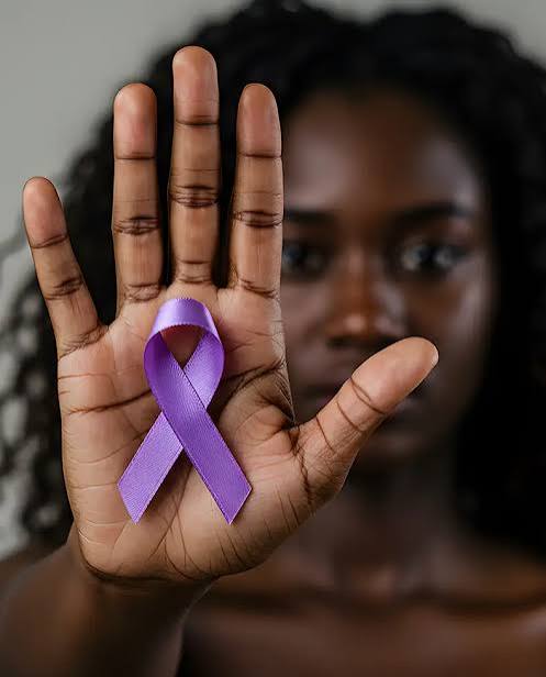 A dark-skinned person with curly hair holding a palm up with a purple ribbon representing Domestic Violence Awareness