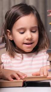 Un niño pequeño sostiene un libro abierto y lee 4K, Motion Graphics  Incluyendo: kids y background kids