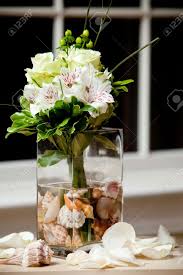 A beautiful white wedding bouquet of orchids and roses, with some greenery is classics. A Wedding Bouquet In A Vase Filled With Water And Sea Shells Stock Photo Picture And Royalty Free Image Image 13057965
