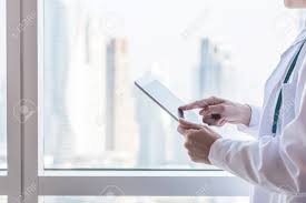 Are you having difficulties with achieving or maintaining an erection, lasting a long time in the bedroom? Doctor Or Physician Holding Mobile Tablet Working On Patient S Health Record In Medical Clinic Office Or Hospital With City Office Building Background For Online Healthcare Assistance Service Concept Stock Photo Picture And