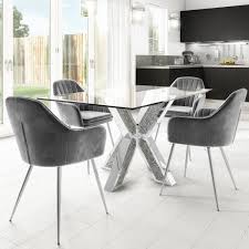 Contemporary dining room features a brass and glass sputnik chandelier illuminating a wood and chrome dining table lined with gray leather dining chairs atop a gold and gray rug. Jade Boutique Chrome Glass Dining Table With 4 Logan Grey Tub Chairs Furniture123
