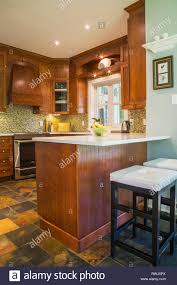 White cabinets with cherry stain floor wood floor kitchen. Kitchen With Earth Tone Slate Flooring Cherrywood Cabinets And Island With White Quartz Countertop Inside A Contemporary Cottage Style Home Quebec Canada This Image Is Property Released Pr0062 Stock Photo Alamy