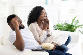 Young black family couple watching comedy movie on tv Stock Photo ...