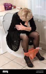 Blonde Frau auf der Toilette sitzt mit den Händen auf den Kopf Distressed  Stockfotografie - Alamy