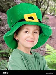 Un garçon portant un chapeau de lepretchun vert tient un verre de boisson  verte et le tient devant lui à l'appareil photo. Fête de la Saint Patrick  Photo Stock