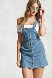 A Denim Overall Dress Featuring A Buttoned Placket Adjustable Shoulder Straps Mini Chest Patch Pocket And Fro Jean Overall Dress Denim Overall Dress Fashion