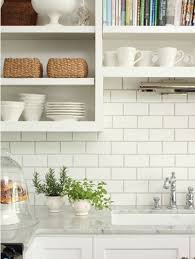 The dark gray cabinets serve as nice contrasts to the lightness of the space that can also be seen in the white counter and subway tile backsplash. White Kitchen With White Tiles And Grey Grout Novocom Top