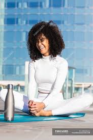 Butterfly pose is very good for opening out hips and strengthening our inner. Happy Brazilian Woman Sitting In Butterfly Pose On Mat With Eco Friendly Water Bottle During Yoga Training Flexible Position Stock Photo 459302644