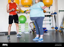 Low Section Portrait Of Obese Young Woman Exercising With Jumping Rope During Weightloss Training In Gym With Personal Fitness Coach Copy Space Stock Photo Alamy