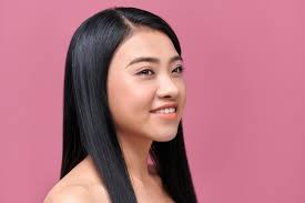 Bella mujer asiática con piel lisa y cabello largo y negro sobre un fondo  rosa