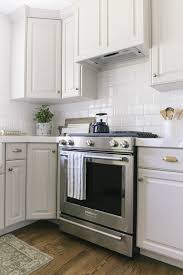 Light Gray Kitchen Cabinets Warm Gray White Subway Tile With White Grout Brass Cup P Kitchen Renovation Replacing Kitchen Countertops Light Grey Kitchens