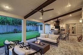 A covered up patio with ceiling fan overlooks a concrete coffee table surrounded by beautiful fabric furnishing onlooking an outdoor fireplace. Beautiful Patios Archives Texas Custom Patios