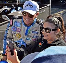 Family moment photo with John Force and his daughter Brittany Force at a  racing pit stop.