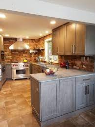 Rustic ceiling beams accent a vaulted kitchen ceiling holding mirrored lanterns over a light brown wooden island accented with a marble countertop seating dark gray leather stools. Modern Rustic Kitchen In Grey And Brown Transitional Kitchen Burlington By Zobel Co Kitchens Houzz