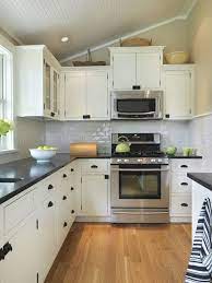White kitchen cabinets adorned with gold and black pulls are fixed against blue and gray marble hexagon backsplash tiles above blue lower black fabric counter stools sit at a black quartz countertop accenting a raised breakfast bar fitted to an ivory kitchen island boasting glass front. Pin By Ag Carpenter On Leigh House Interiors Freestanding Kitchen Black Kitchen Countertops Kitchen Remodel Small