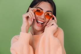 Young stylish woman in casual peach sweater and orange glasses isolated