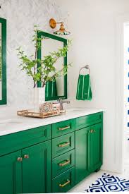 Green And Neutral Bathroom With Mirrors Patterned Wallpaper And Blue And White Rug Green Cabinets Bathroom Trends Green Bathroom