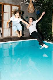Young Couple Wearing All Their Clothes Splashes Into Pool During Spontaneous Summer Night Time Swim Night Time Photography Summer Poses Couple Photoshoot Poses