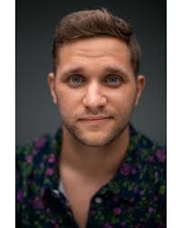 New directing headshot by Daniel Stemen, featuring a thrifted flower shirt  and the soft grin of a man who just remembered that it's Thin Mint season