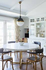 The base is made of cast aluminum and features a glossy white finish that complements the natural marble. Round Brass And Marble Dining Table With Vintage Chairs Transitional Dining Room
