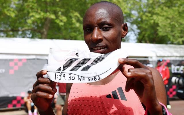 Sabastian Sawe holding up his shoe marked with world record time