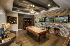A Brick Accent Wall And Dramatic Beams Add A Timeless Look To This New Home Built By Ashton Woods Homes The Rid Pool Table Room Game Room Basement Family Room