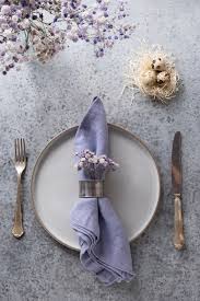 Ajuste de la tabla violeta de Pascua con huevos blancos en nido y  decoración lila en mesa gris. Cena de elegancia. Vista superior. Formato  vertical.