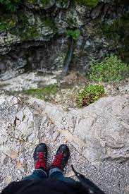 Legs Of A Person On The Edge Of A Drop Off Looking Down Into The Valley By Denni Van Huis