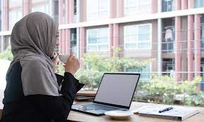happy beautiful muslim female worker holding hot coffee mug sitting in  office and using mobile cell phone viewing online news relaxing. 8740840  Stock Photo at Vecteezy