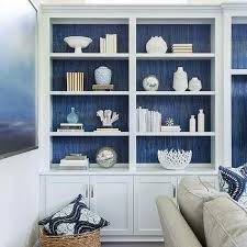 Blue Textured Wallpaper Behind White Bookshelves Bookshelves In Living Room Living Room Shelves White Bookshelves