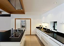 Idées déco pour une cuisine américaine parallèle contemporaine avec un évier posé, un placard à porte plane, des portes de placard blanches, une crédence blanche, un électroménager noir, un îlot central, un sol gris et un plan de travail noir. Cuisine Blanche Bois Et Noire Cuisine Contemporaine Cuisines Design Idee Deco Cuisine Ouverte