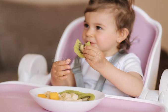 Retrato De Crian&ccedil;a Feliz Comendo Kiwi Em Alta Cadeira. Nutri&ccedil;&atilde;o Saud&aacute;vel  Para Crian&ccedil;as Imagem de Stock - Imagem de infante, atolamento: 182944893