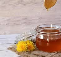 Natural honey in a transparent jar with flowers as ...