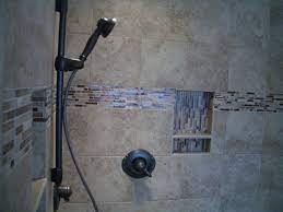 White subway tiled shower with glass door and gold accents. Glass Tiles As Accents In Tile Installations