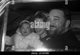 Singer-comedian Michael Flanders arrives by car at Buckingham Palace to  receive his OBE. In the car with him are his American wife, Claudia, and  two-year-old daughter Laura Stock Photo