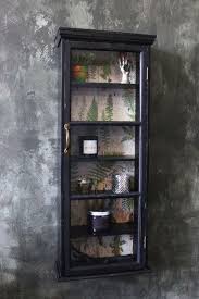 This linen cabinet is modeled in a cottage style with its vintage detailing, distressed gray/white finish, and antique bronze hardware. Tall Slim Distressed Black Wall Cabinet With Botanical Lining Glass Cabinets Display Black Walls Wall Cabinet