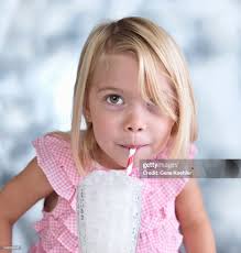 Portrait Of Cute Female Toddler Blowing Bubbles In Glass Of Milk High-Res  Stock Photo