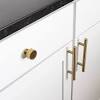 Beautiful white and gold kitchen is fitted with white shaker bar cabinets topped with a calacatta marble countertop fixed beneath stacked glass shelves mounted on a gold and gray metallic wallpaper between floor to ceiling white cabinets. 1