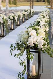 Lantern Aisle Markers With White Flowers Double As Centerpieces Ceremony Flowers Aisle Wedding Aisle Decorations Wedding Ceremony Flowers