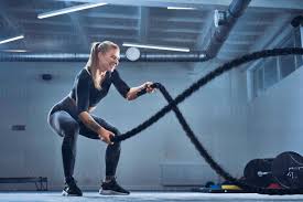 Athletic woman exercising with battle ropes at gym stock photo