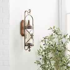 Fashioned from solid brass and adorned with medallions and scrolls, a sconce pair is the perfect way to frame a mirror trimmed with golden acanthus leaves. Harper Willow Metal Lantern Wall Sconce With Fleur De Lis Hurricane Glass 68391 At Tractor Supply Co
