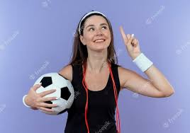 Junge Fitnessfrau Im Stirnband Mit Springseil Um Den Hals Der Fussball Zeigt Der Oben Mit Dem Finger Zeigt Der Oben Lachelnd Neue Idee Hat Die Uber Blaue Wand Steht Kostenlose Foto