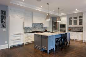 White cabinets with marble counter top, dark island with white marble countertop, medium the mosaic rug above the stove is calacatta oro, timber grey & lagos blue. Elegant Leaside Custom Home By Steffanie Gareau