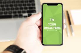A Mockup Featuring A Man Holding An Iphone X On A Blurred Office Desk Background A Great Template For Showcasing Your Ios App Iphone Mockup Laptop Backgrounds