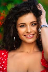 Bella ragazza riccia mora in costume rosso zingaro e accessori in posa  sulla natura con sorbo